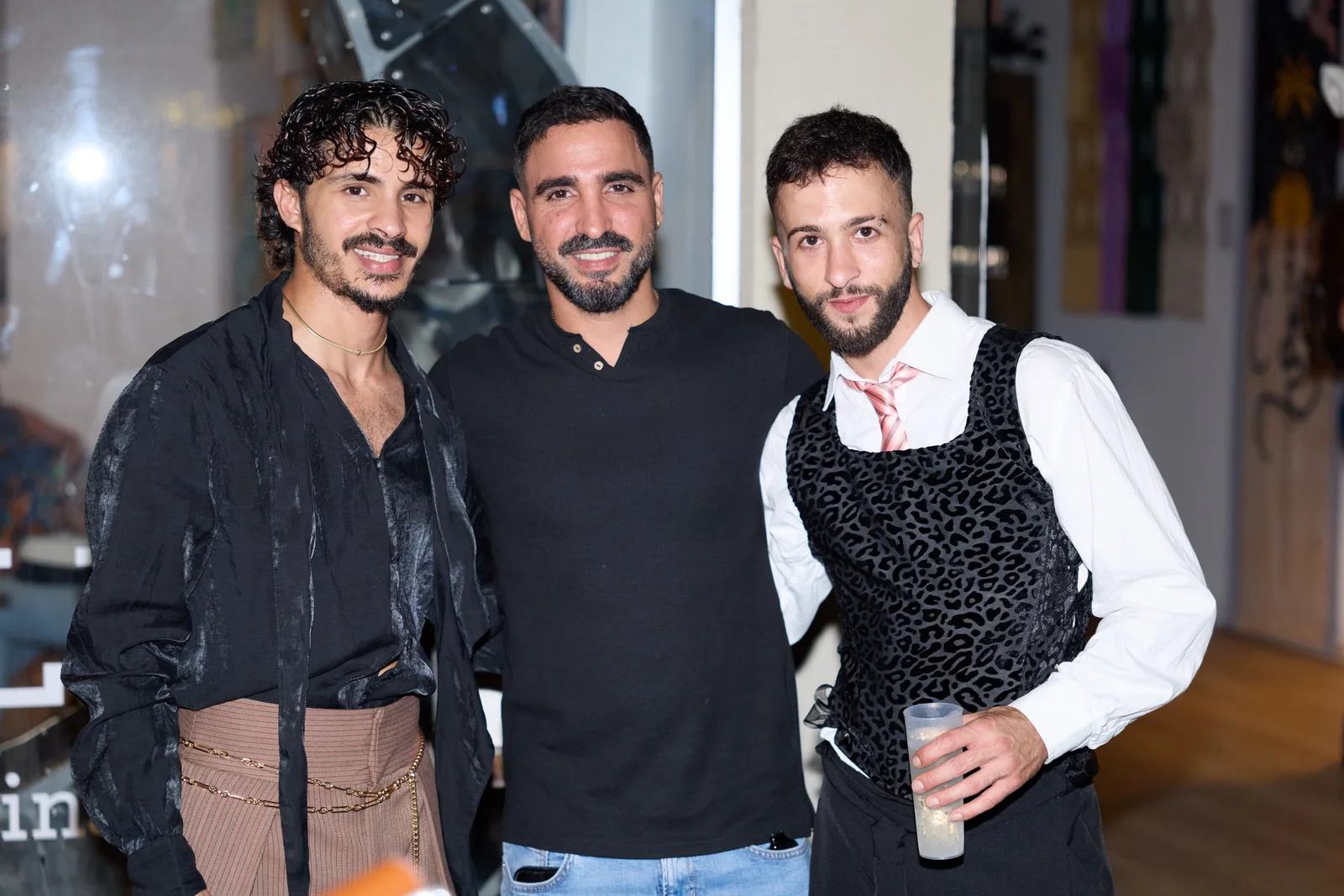 שלושה משתתפים מצטלמים יחד בחלל הגלריה