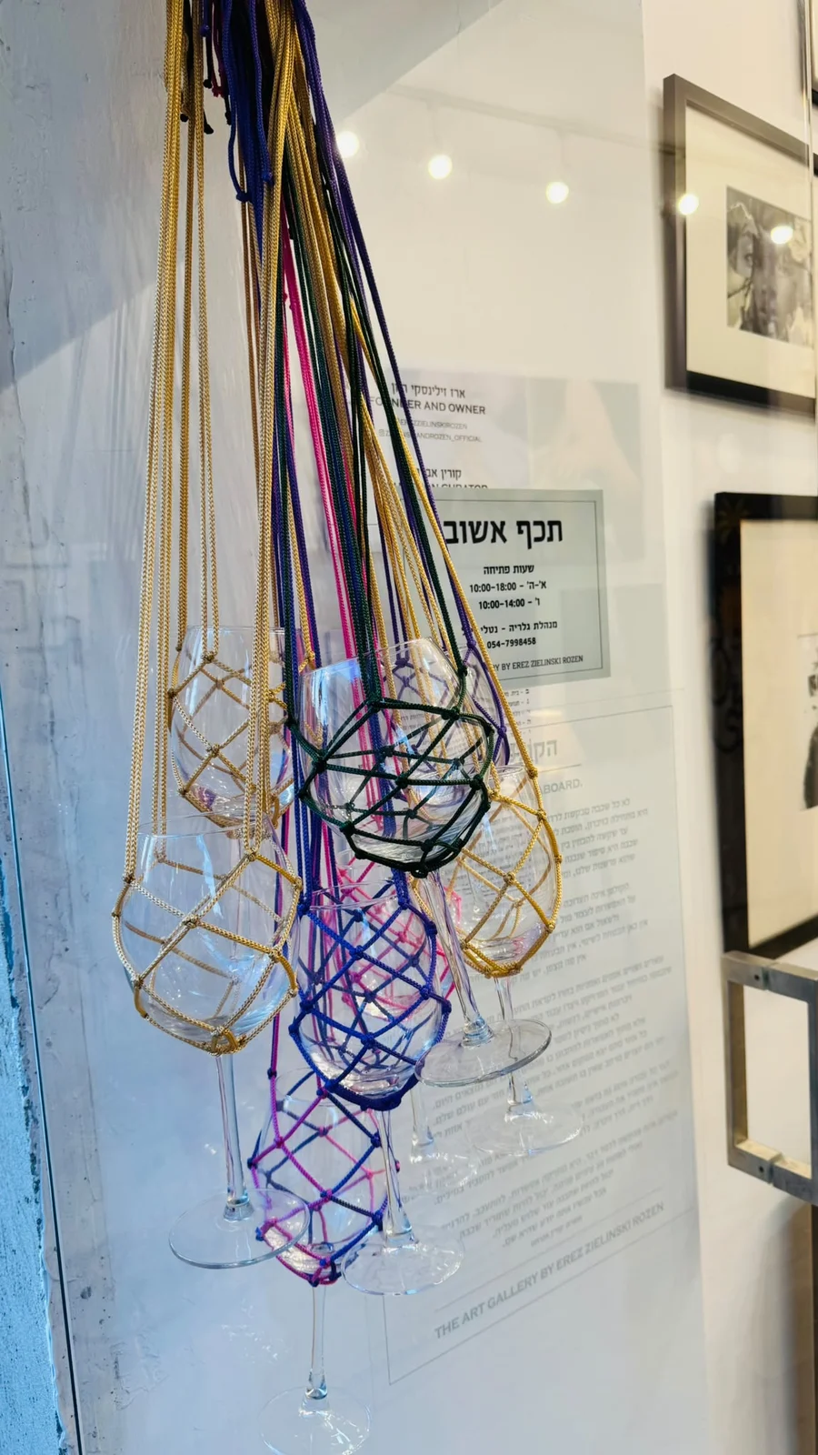 כוסות יין עטופות ברשתות מקרמה צבעוניות תלויות בחלון הגלריה