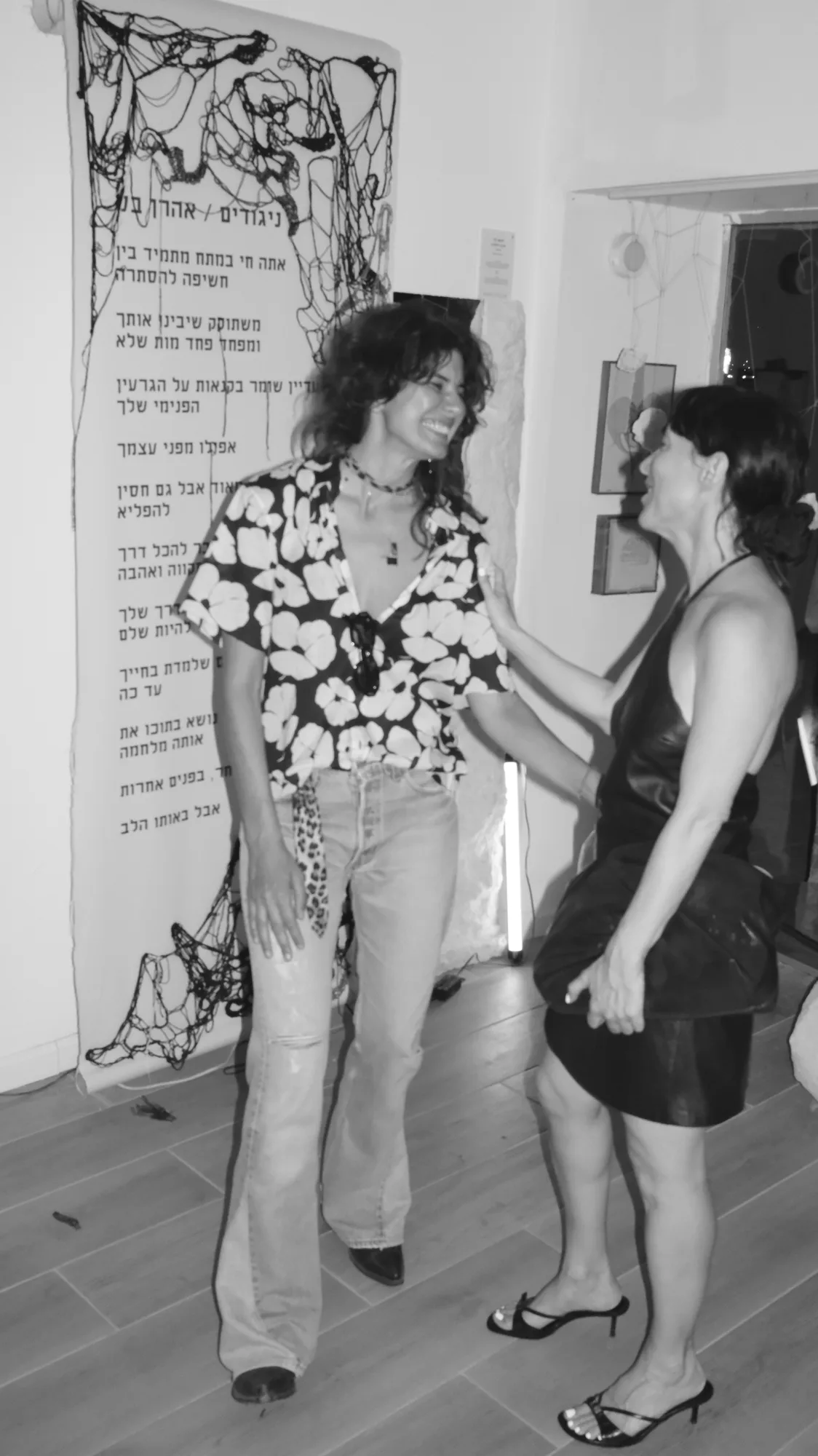 האמנית משוחחת עם מבקרת ליד טקסט התערוכה
